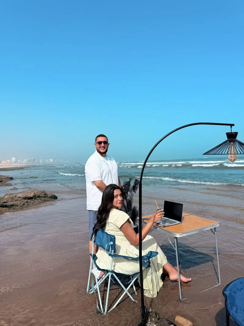 Deux membres de l’équipe à un bureau installé dans l’eau, au bord de la plage